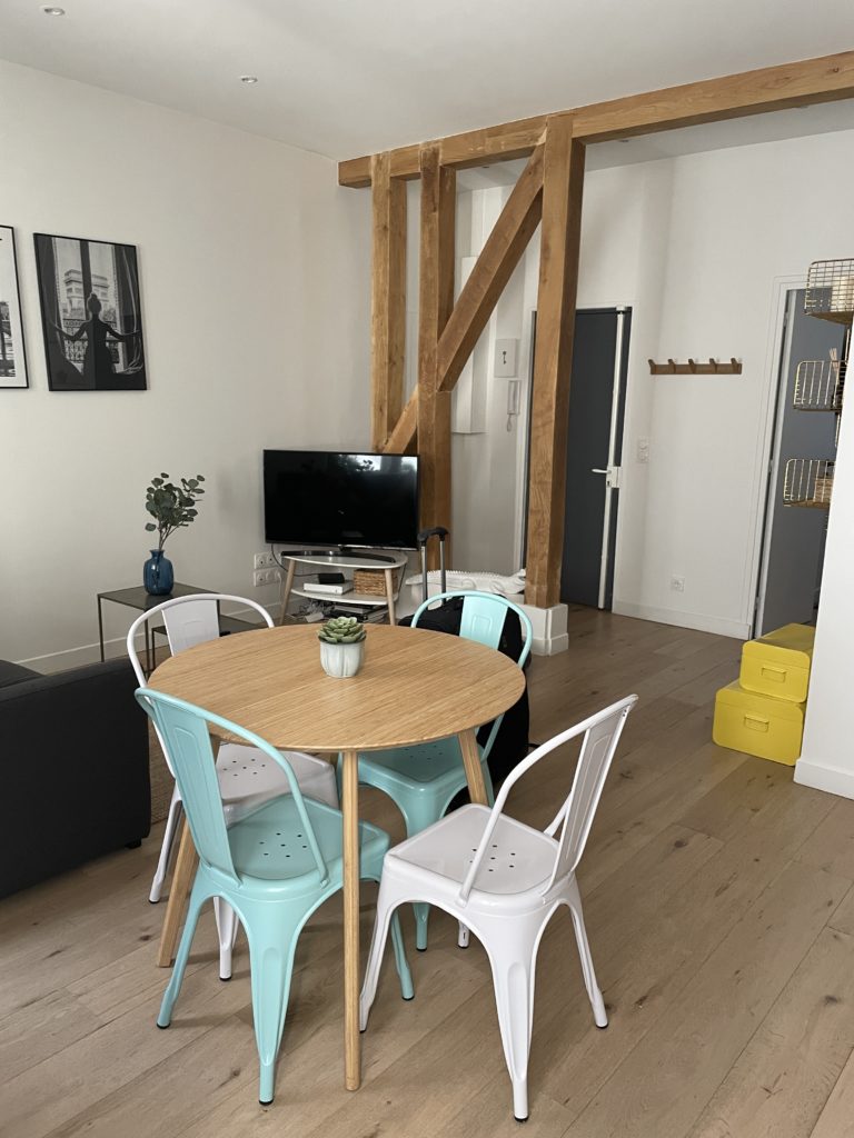 a dining table and TV are shown in a Paris Airbnb