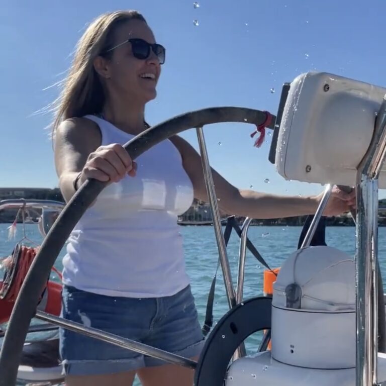 a woman is behind the helm of a sailboat on Lago di Garda