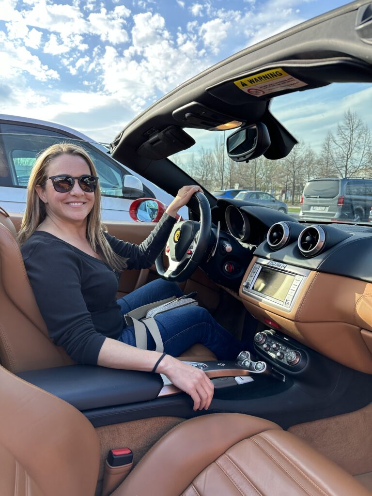 A woman sitting in the driver's seat of a Ferrari convertible.