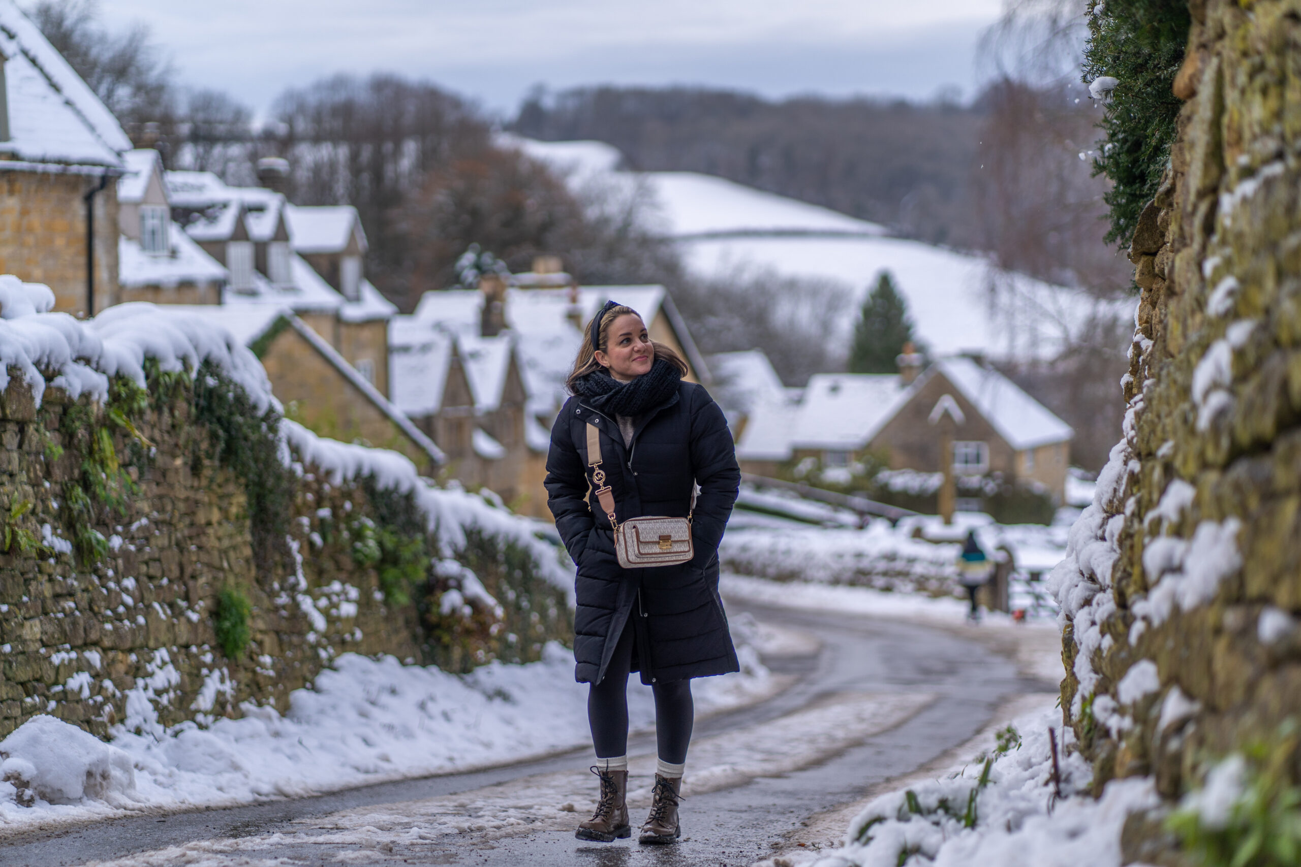 The Cotswolds a woman walks down a slushy road in Snowshill England in the Cotswolds looking out at the snow