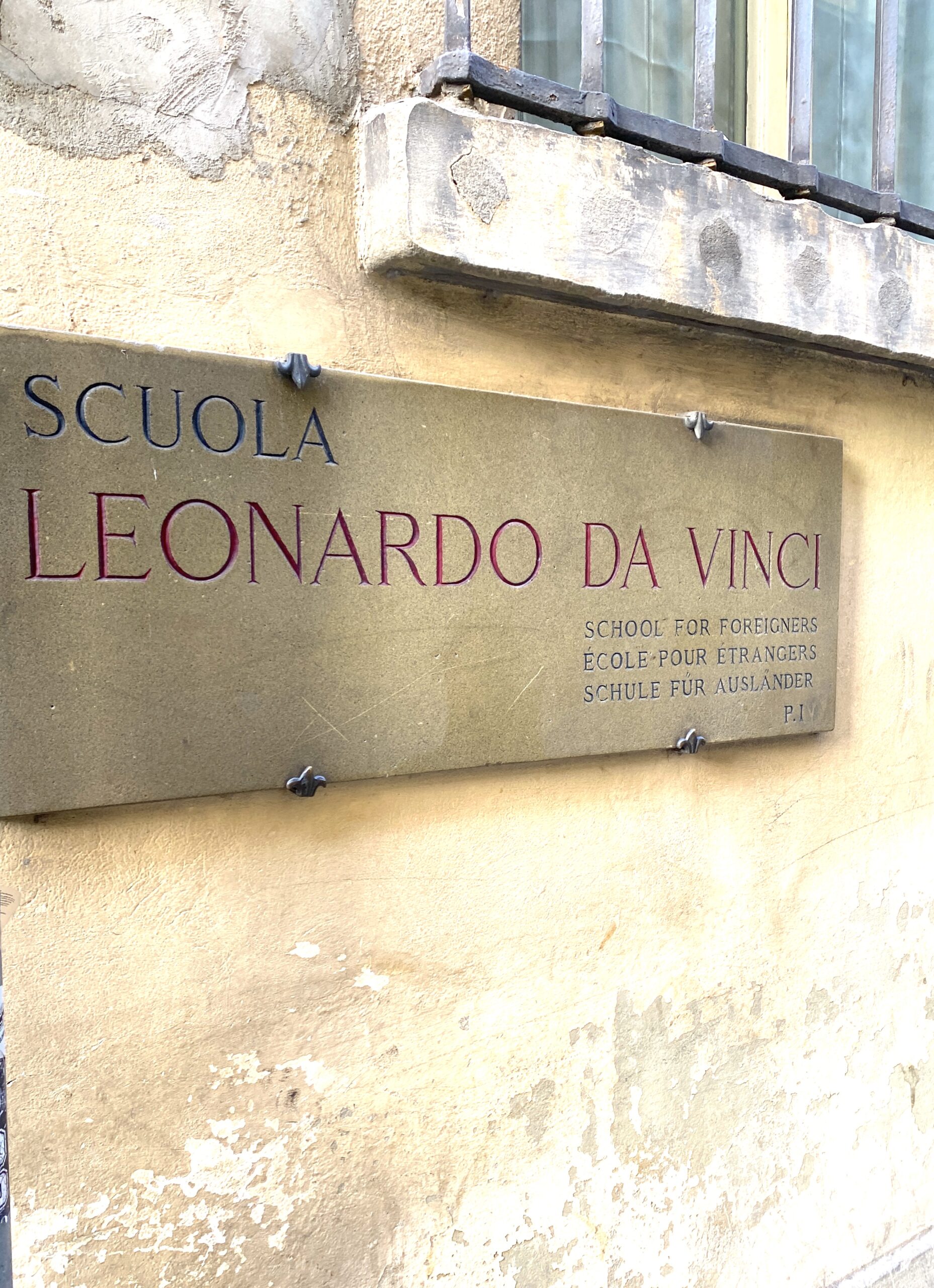 a sign for Scuola Leonardo da Vinci is on the side of a stone building in Florence