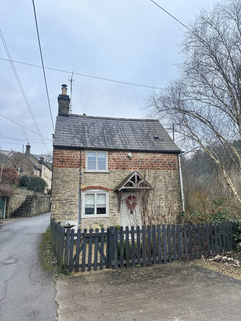 Chalford Cottage Cotswolds 24 Charming stone cottage in Chalford, Cotswolds, featuring a classic brick and stone exterior with a pitched roof and a quaint front garden, ideal for a cozy holiday escape.