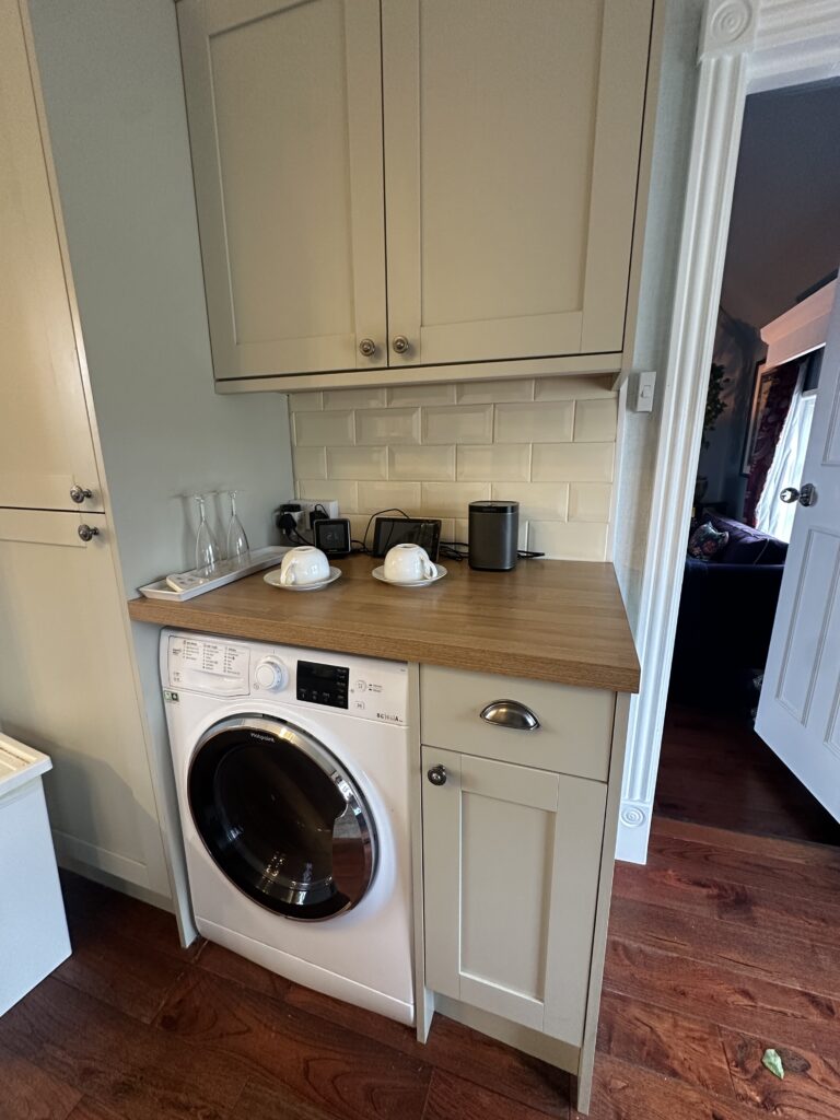 Stratford Upon Avon Penthouse 10 Compact laundry corner in a Stratford-Upon-Avon penthouse kitchen, with integrated washer, countertop, and storage cabinetry for convenience.