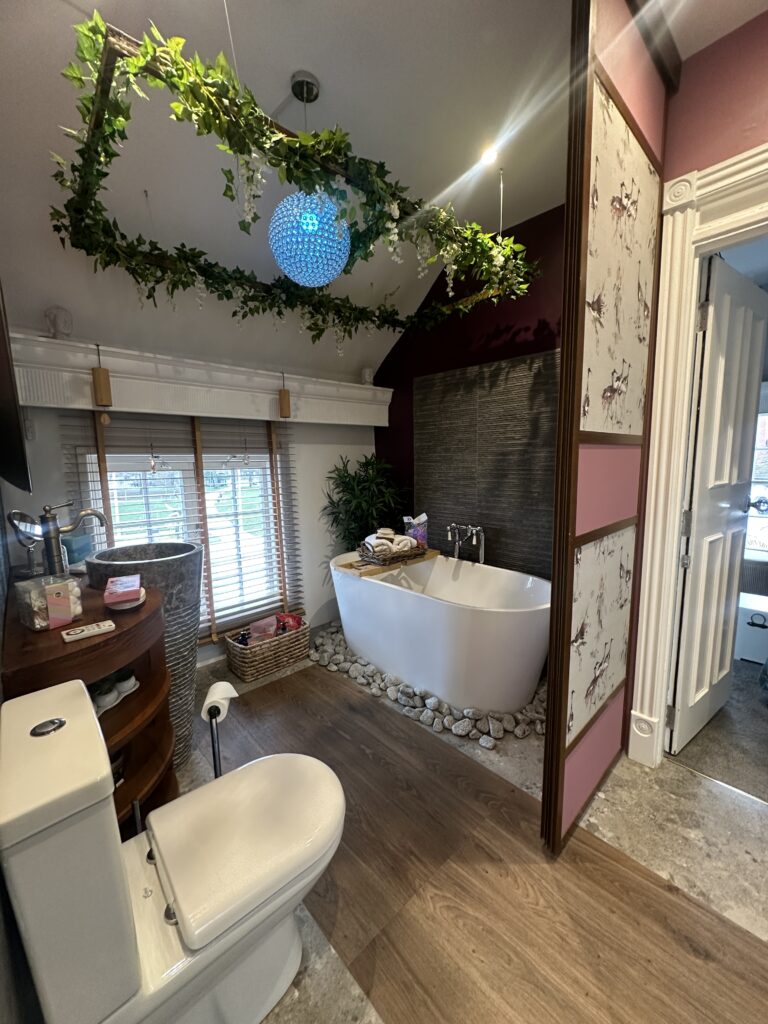 Stratford Upon Avon Penthouse 4 Luxurious bathroom in a Stratford-Upon-Avon penthouse, featuring a freestanding bathtub, ambient greenery, and elegant lighting for a spa-like experience.
