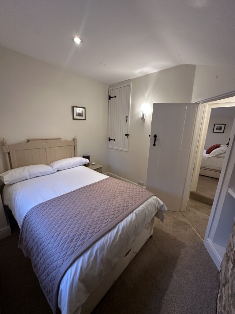 Charming second bedroom with a small double bed and antique-style headboard at Lane’s Cottage in the Cotswolds.