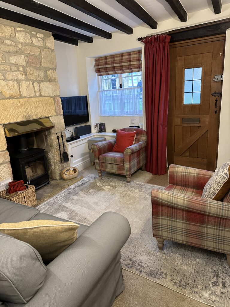 Warm and welcoming living room at Lane’s Cottage with plaid armchairs, a traditional front door, and countryside charm.