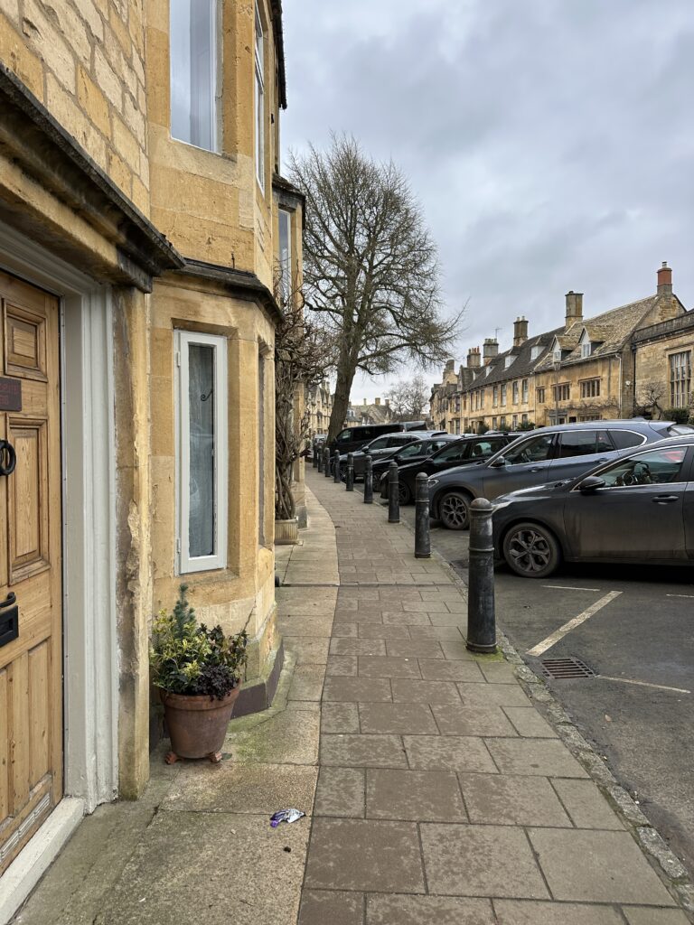 Charming view of Chipping Campden High Street with historic Cotswold buildings and shops near Lane’s Cottage.