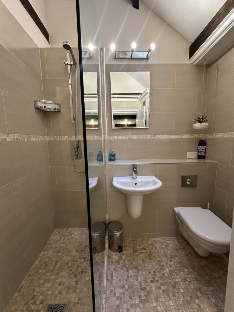 Contemporary walk-in shower with neutral tiling in the updated bathroom at Lane’s Cottage in the Cotswolds.